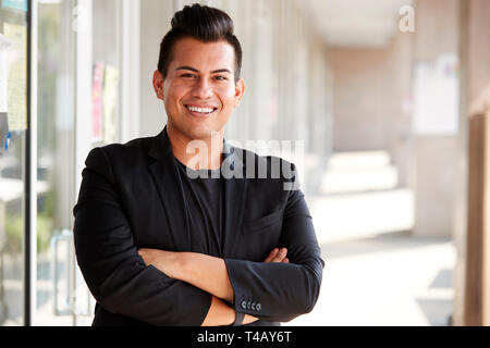Portrait Of Smiling Male School Teacher Standing In Corridor Of College Building Stock Photo