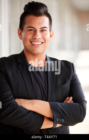 Portrait Of Smiling Male School Teacher Standing In Corridor Of College Building Stock Photo