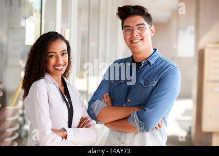 Portrait Of Smiling Male And Female School Teachers Standing In Corridor Of College Building Stock Photo