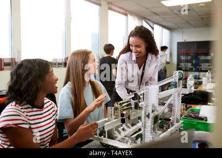 Woman Teacher With Female College Students Building Machine In Science Robotics Or Engineering Class Stock Photo