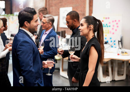 Business Team Socializing At After Works Drinks In Modern Office Stock Photo