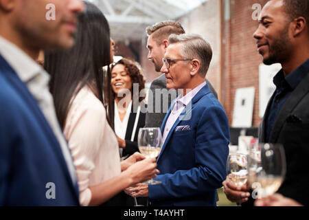 Business Team Socializing At After Works Drinks In Modern Office Stock Photo