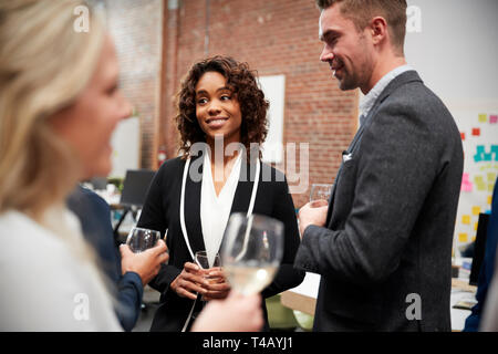 Business Team Socializing At After Works Drinks In Modern Office Stock Photo