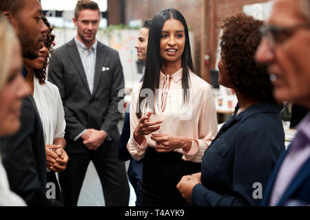 Business Team Standing Having Informal Meeting In Modern Office Stock Photo