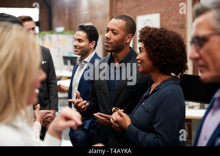 Business Team Standing Having Informal Meeting In Modern Office Stock Photo