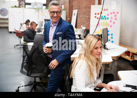 Businessman And Businesswoman Working At Laptop On Desk In Open Plan Office Stock Photo