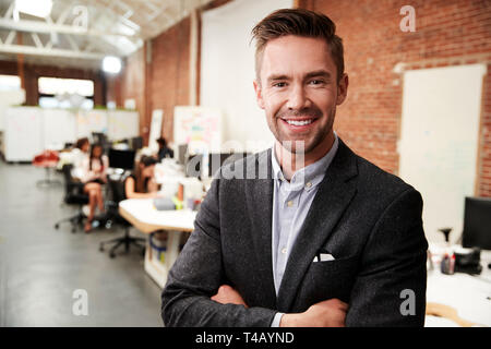 Portrait Of Businessman In Modern Open Plan Office With Business Team Working In Background Stock Photo