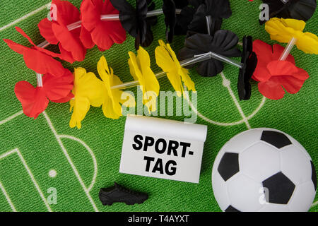 Sporttag german language means Sports Day. Soccer Ball with flower necklace in the colors of german flag and calendar Stock Photo