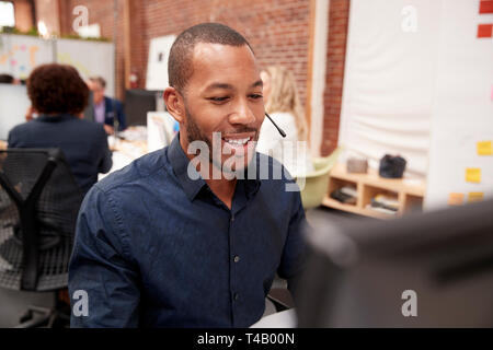 Male Customer Services Agent Working At Desk In Call Center Stock Photo
