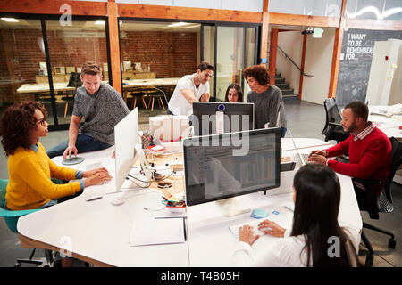 Casually Dressed Business Team Working At Desks In Modern Open Plan Office Stock Photo