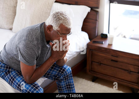 Depressed Senior Man Looking Unhappy Sitting On Side Of Bed At Home With Head In Hands Stock Photo