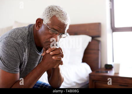 Depressed Senior Man Looking Unhappy Sitting On Side Of Bed At Home With Head In Hands Stock Photo