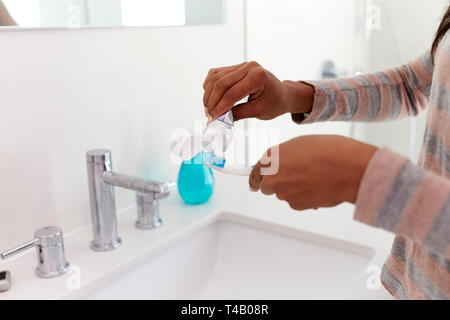 Close Up Of Woman Squeezing Toothpaste Onto Toothbrush In Bathroom Stock Photo