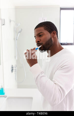 Man Looking At Reflection In Bathroom Mirror Brushing Teeth Stock Photo