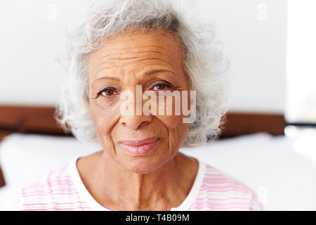 Portrait Of Depressed Woman Looking Unhappy Sitting On Side Of Bed At Home Stock Photo