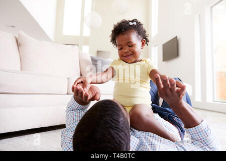 Baby Daughter Playing With Father In Lounge At Home Stock Photo
