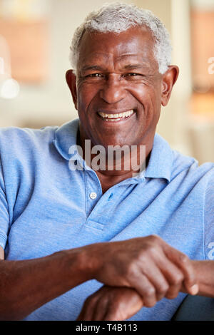 Portrait Of Smiling Senior Man Relaxing On Sofa At Home Stock Photo