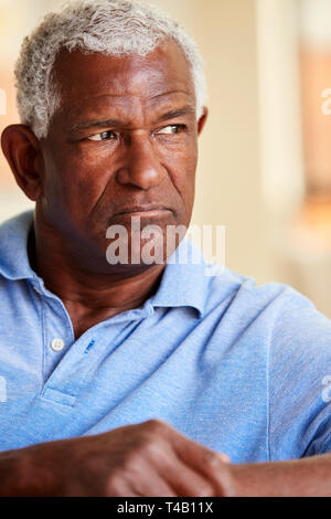 Thoughtful Senior Man Sitting On Sofa At Home Stock Photo