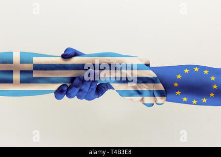 New way of relation. Male hands holding colored in EU and Greece flag isolated on gray studio background. Concept of help, commonwealth, partnership of countries, political and economical relations. Stock Photo