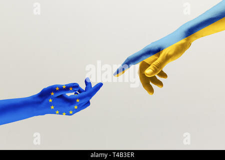 The creation of Adam. Two male hands colored in flag of European Unity and Ukraine isolated on grey studio background. Concept of help, partnership of countries, political and economical relations. Stock Photo
