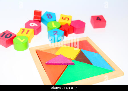 Multi-colored cubes and figures with numbers laid out randomly on a white background. Children learn to design from colored cubes. Wooden toys for chi Stock Photo