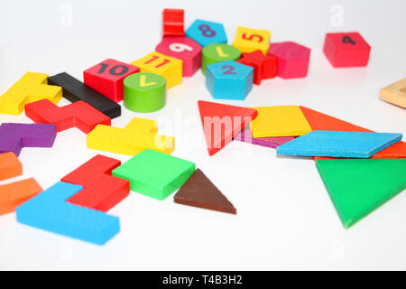 Multi-colored cubes and figures with numbers laid out randomly on a white background. Children learn to design from colored cubes. Wooden toys for chi Stock Photo