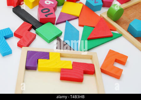 Multi-colored cubes and figures with numbers laid out randomly on a white background. Children learn to design from colored cubes. Wooden toys for chi Stock Photo