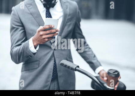 Businessman texting on phone leaning on the handlebars Stock Photo
