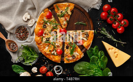 Hot pizza with tomatoes and herbs on cutting board Stock Photo