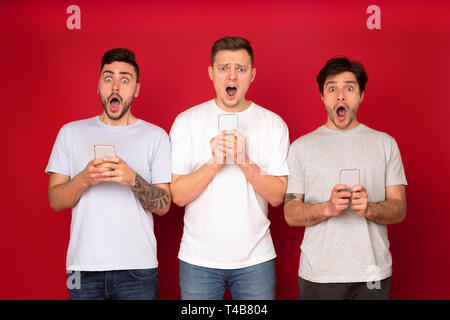 Shocked male friends with phones, surfing the internet Stock Photo