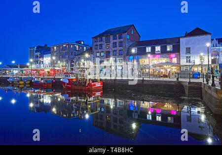 Skyline of Barbican Quay on the harbour of Plymouth with fishing vessels reflected at twilight Stock Photo