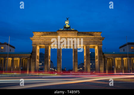 Traffic's light trails in front of the famous and illuminated Brandenburg Gate (Brandenburger Tor) in Berlin, Germany, in the evening. Stock Photo