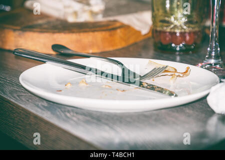 Knife and fork on dirty plate Stock Photo