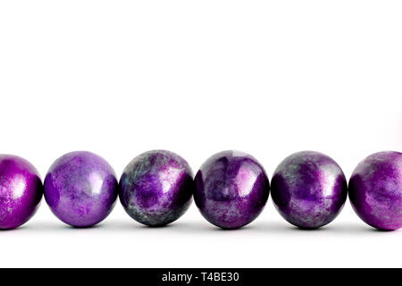 Easter eggs decorated in different shades of violet lined on isolated white background. Close-up. Stock Photo