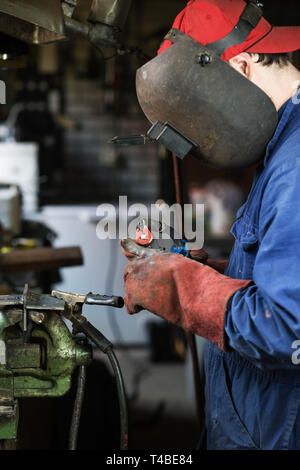 welder cuts iron from welding machine, welder is welding in the garage Stock Photo