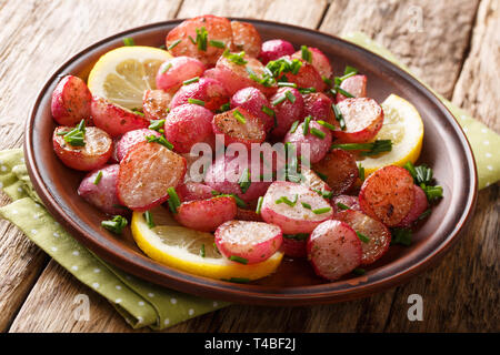 Crispy fried radish with lemon and green onions close-up on a plate on the table. horizontal Stock Photo