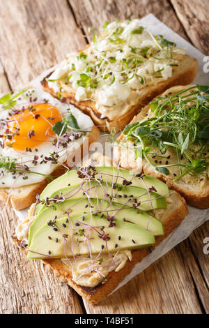 Healthy sandwiches with hummus, avocado, feta cheese, microgreen and egg closeup on the table. vertical Stock Photo