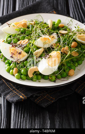Easter green peas salad, micro green, nuts and boiled eggs close-up on a plate on the table. vertical Stock Photo