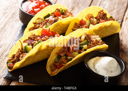 Mexican fast food tacos with chopped beef, cheese and vegetables served with sauces close-up on a slate board on the table. horizontal Stock Photo