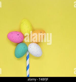 Flower made of colourful Easter eggs, against a yellow background Stock Photo