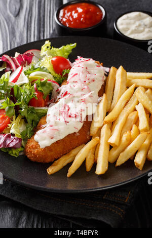 Lunch menu fried pollock with french fries and fresh salad close-up on a plate and sauces on the table. vertical Stock Photo
