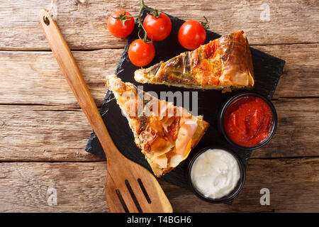 Delicious pie stuffed with salmon, tomatoes, cheese and herbs close-up on the table. horizontal top view from above Stock Photo