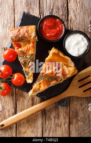 Sliced quiche stuffed with salmon, tomatoes, cheese and herbs close-up on the table. Vertical top view from above Stock Photo