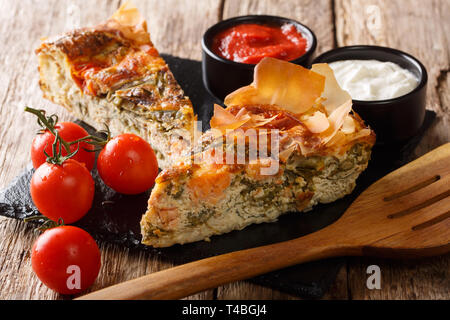 Freshly baked pie with salmon, tomatoes, cheese and herbs close-up on the table. horizontal Stock Photo