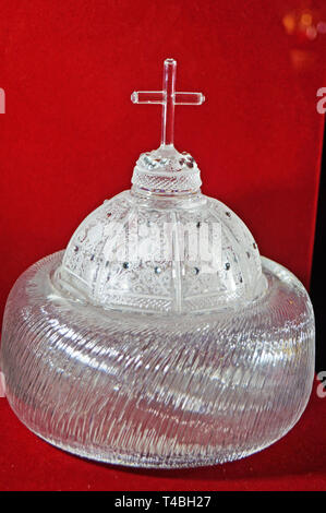 The royal crown made of crystal lies on a red velvet stand Stock Photo