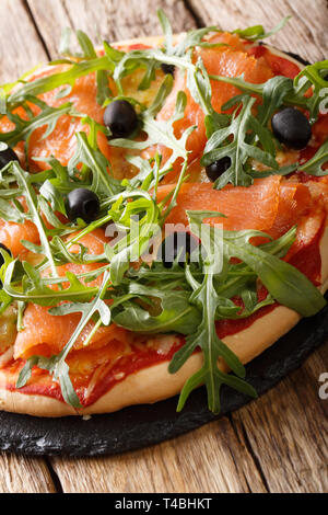 Delicious pizza with salted salmon, arugula, olives and cheese closeup on the table. vertical Stock Photo