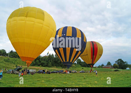 Balloons of yellow, blue, white are inflated before flying on a green glade on a summer day. Stock Photo