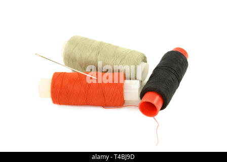 Spools with multi-colored sewing thread and needle isolated on white Stock Photo