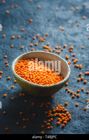 Red lentils in a bowl close up on dark stone background Stock Photo