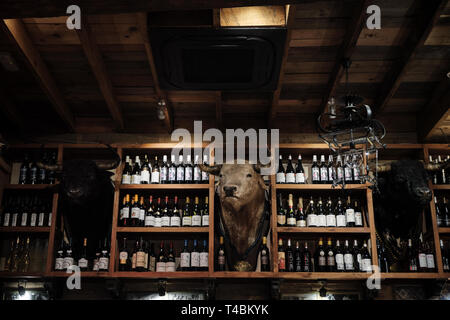 April 2019 - Seville Spain Typical Tapas restaurant interior with bottle of wine and stuffed bull head embalm Stock Photo